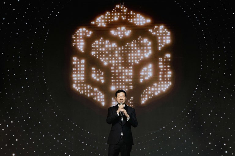 Varut Bulakul, CEO of The Brooker Group PCL, delivering the opening remarks on stage at the BNB 1K Gala Night in front of a glowing digital display backdrop.