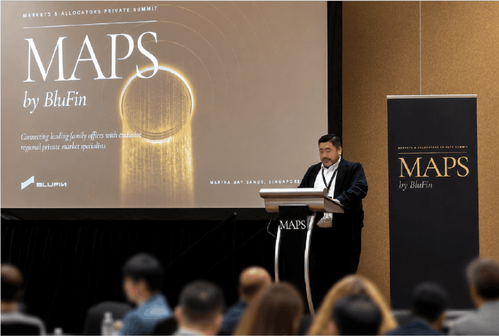 Male speaker at a podium during the MAPS by BluFin summit at Marina Bay Sands, Singapore, addressing a seated audience.