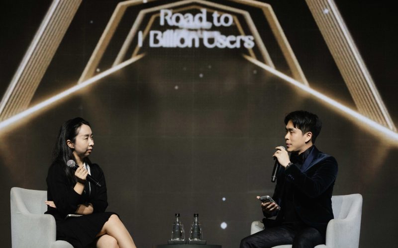Sarah Song, Head of Business Development at BNB Chain, and Varit Bulakul, President of Business Consulting at The Brooker Group PCL, in conversation on stage under a screen reading "Road to 1 Billion Users".