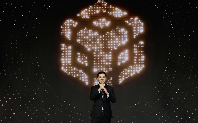 Varut Bulakul, CEO of The Brooker Group PCL, delivering the opening remarks on stage at the BNB 1K Gala Night in front of a glowing digital display backdrop.