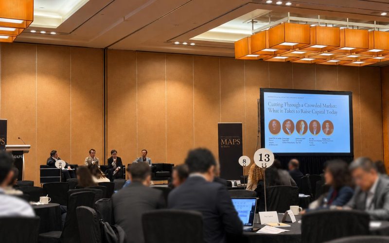 Panel discussion on "Cutting Through a Crowded Market: What It Takes to Raise Capital Today" at the MAPS by BluFin conference, featuring speakers on stage before an audience seated at round tables.